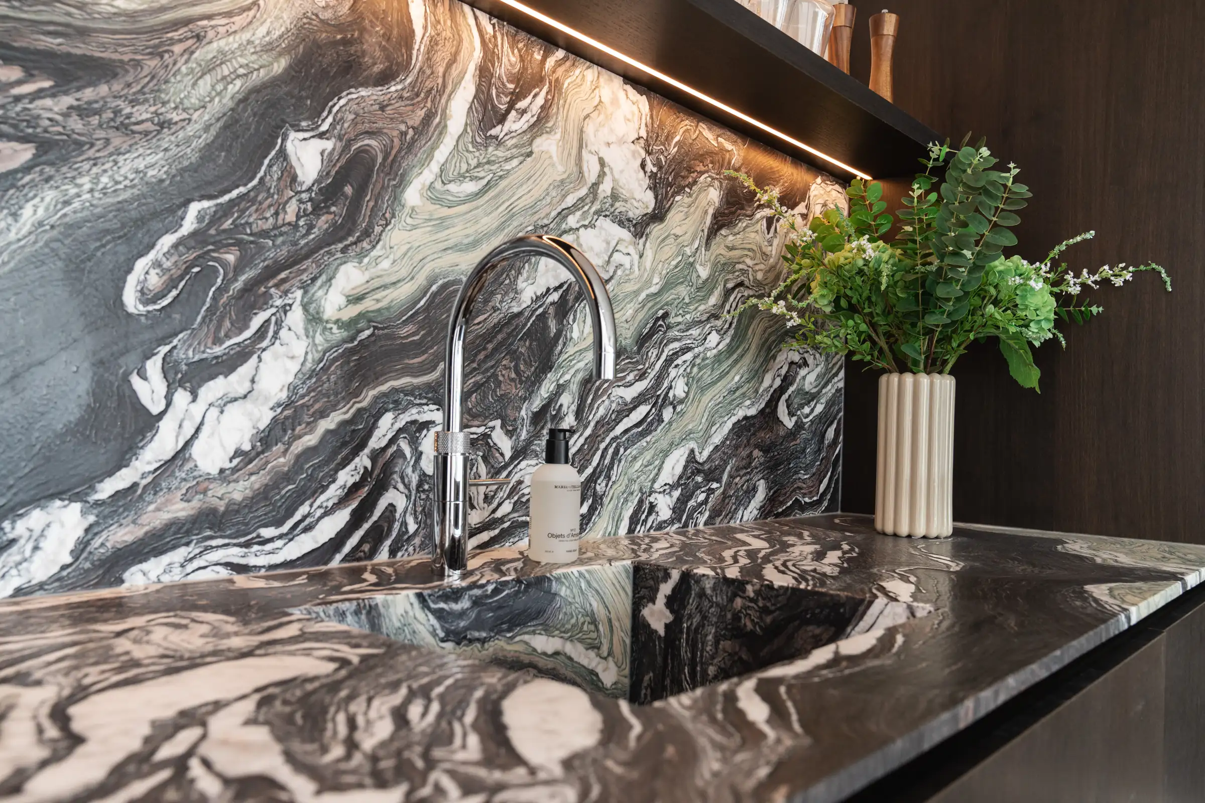 Spoelbak en kraan in een natuurstenen keukenblad met achterwand in de showroom van Wagemaker Marmer & Graniet in Middelharnis